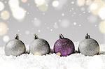 silver and purple decorative christmas balls on snow against grey festive background