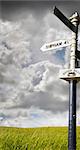 Old signpost with stormy sky and grassy field in the countryside in Sommerset, England