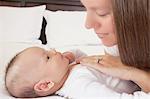 Mother admiring baby boy lying on bed