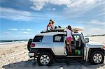 Two young girls untying surfboards from top of car