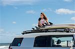 Young girl on top of car, looking at view