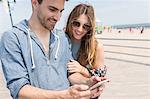 Couple looking at smartphone smiling, Coney island, Brooklyn, New York, USA