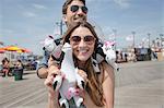 Couple holding cuddly toy cows smiling, Coney island, Brooklyn, New York, USA
