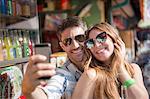 Couple using smartphone to take selfie, Coney island, Brooklyn, New York, USA
