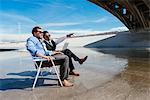 Businessmen sitting in deckchairs on Los Angeles river, California, USA