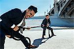 Businessman doing tug of war with rope, Los Angeles river, California, USA