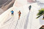 Two women and man training, running up sport facility stairway, downtown San Diego, California, USA