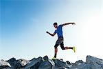 Man training, running on coast rocks, downtown San Diego, California, USA