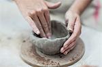 Hands of female potter shaping clay pot in workshop