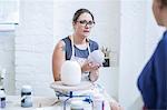Female potter explaining glaze to trainee in workshop