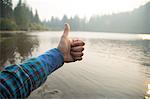 Female hand giving thumbs up over misty lake, Mount Hood National Forest, Oregon, USA