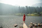 Woman wrapped in tartan blanket looking out over misty lake, Mount Hood National Forest, Oregon, USA