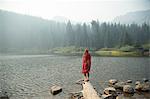 Woman wrapped in tartan blanket looking out over misty lake, Mount Hood National Forest, Oregon, USA