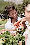 Mature couple holding crate of fresh vegetables in garden