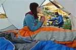 Man preparing breakfast for girlfriend in tent at Fault Lake, Selkirk Mountains, Idaho