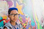 Portrait of teenage boy with blue hair leaning against wall mural at amusement park