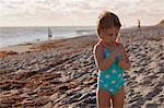 Girl examining stick on beach, Blowing Rocks Preserve, Jupiter Island, Florida, USA