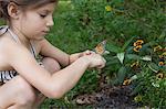 Girl crouching holding monarch butterfly