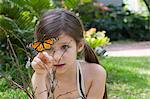 Girl looking at monarch butterfly on plant