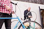 Father and son repairing bicycles outside workshop