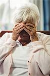 Worried senior woman sitting on sofa in living room