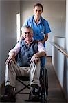 Portrait of smiling senior man and female doctor in corridor at hospital