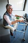 Senior man in hospital trying to stand with the help of walking frame