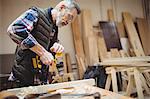 Carpenter drilling a plank of wood in carpentry