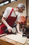 Carpenter cutting a plank of wood in carpentry