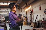 A portrait of a young woman welder with a flaming torch