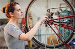 Concentred woman repairing a bicycle wheel in a workshop
