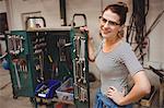 Portrait of smiling woman standing with work tools in a workshop