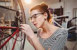 Woman repairing a bicycle wheel in a workshop
