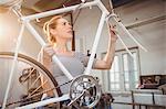 Portrait of a women holding a bicycle in a old workshop