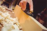 Close-up of carpenter using a sander on a wood plank in his workshop