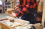 Carpenter working on wooden plank in his workshop