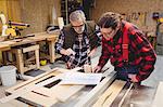 Focused duo of carpenter looking the plan in a workshop