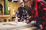 Duo of carpenter working on a wood plank in their workshop