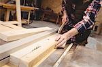 Focus on worker cutting a plank of wood in his workshop