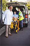 Doctor and ambulance crew taking care of an injured man in front of ambulance vehicle