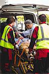 Ambulance crew and doctor taking care of an injured person in front of the ambulance vehicule