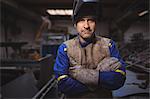 Portrait of confident welder standing with arms crossed in workshop
