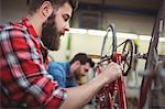 Focus on foreground of mechanic repairing a bicycle in his workshop