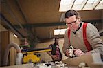 Carpenter leveling a timber with jack plane in workshop