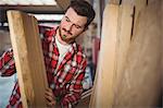 Carpenter looking at wooden plank in workshop