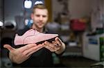 Cobbler holding a shoe in workshop