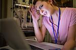 Stressed technician working on laptop in server room