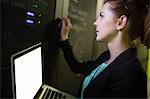 Technician using laptop while analyzing server in server room