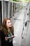 Technician using digital tablet while analyzing server in server room