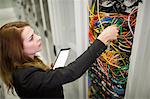 Technician holding digital tablet while examining server in server room